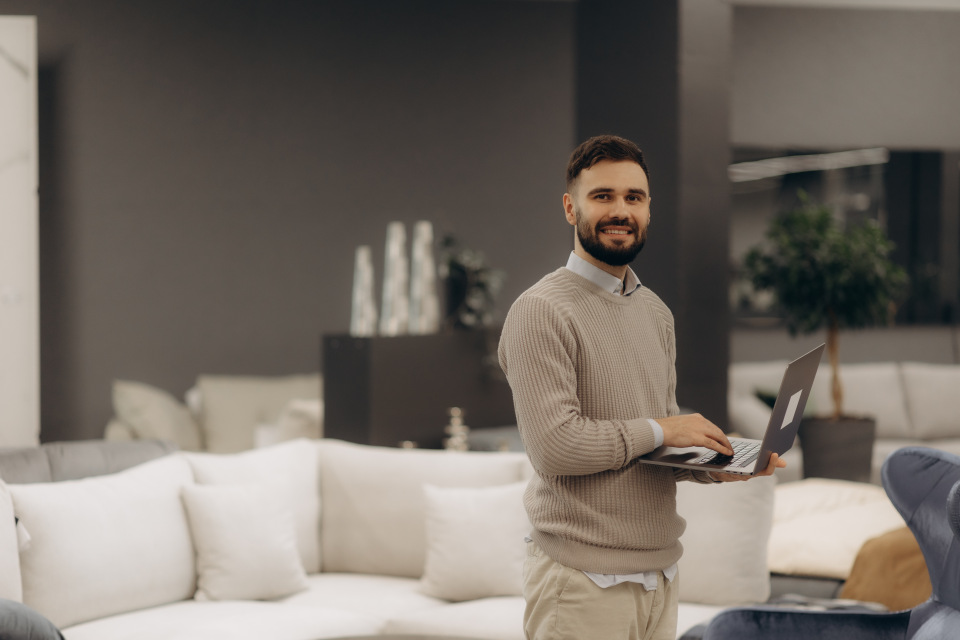 Mann mit Laptop in den Händen in einem edel eingerichteten Zimmer